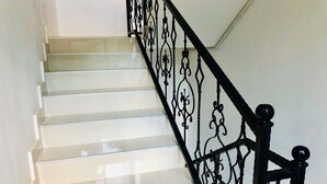 A staircase with white steps and black ornate railings. - Holiday House Green Cape Batumi (Batumi)
