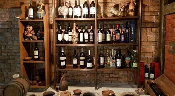 Une cave à vin avec des étagères remplies de bouteilles et un mur en briques au style rustique.