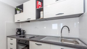 Een koffiezetapparaat/waterkoker, een koelkast, een oven, een kookplaat