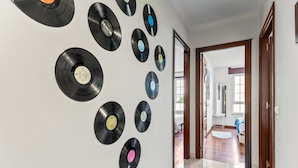 A hallway with a wall decorated with vinyl records, leading to a room with a large window and a door. - Apartment 'O Faro Apartamentos' with Sea View, Balcony and Air Conditioning (Ribadeo)