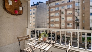 A balcony with a wooden table, two wine glasses, a bottle, and a potted plant. - Apartment 'O Faro Apartamentos' with Sea View, Balcony and Air Conditioning (Ribadeo)
