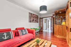 Un salon avec un canapé rouge, des meubles en bois et un fauteuil vert.
