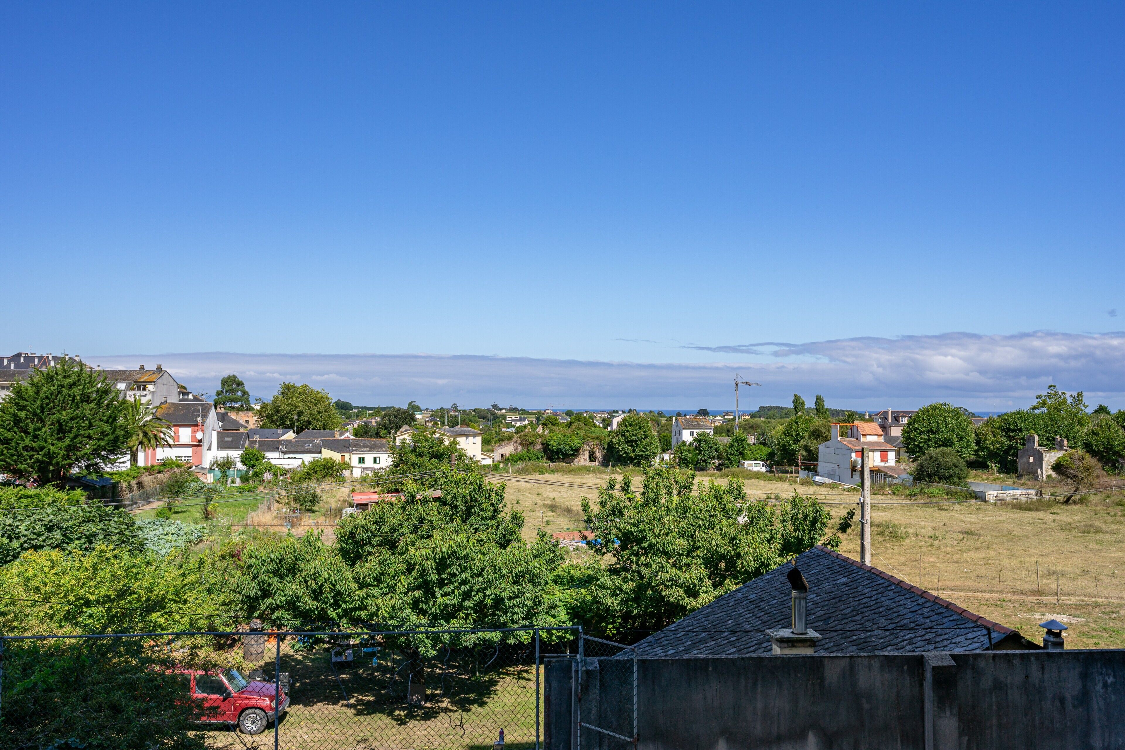 A residential area with houses, a fenced yard, and a clear sky.