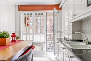 Une cuisine moderne avec des meubles blancs, un plan de travail en bois et une lanterne rouge.