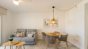 Un soggiorno moderno con un divano grigio, un tavolo da pranzo rotondo in legno e una lampada a sospensione.