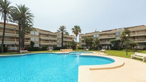Una piscina circondata da palme e un edificio con balconi.