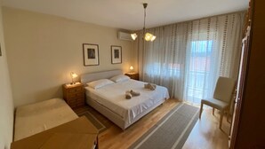 Une chambre à coucher avec un lit, des tables de chevet, une chaise et une fenêtre avec des rideaux.