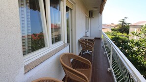 Un balcon avec des fauteuils en osier, une table et une rambarde.