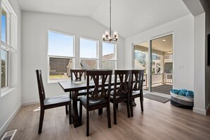 Un espace repas comprenant une table et des chaises, de grandes fenêtres et une vue sur l’extérieur.