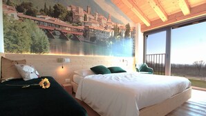 A bedroom with a large bed, two pillows, a nightstand, a wall-mounted lamp, and a window with a view of a river and buildings. - Stunning private villa with WIFI, A/C, hot tub, private pool, sauna, TV and pets allowed (Montebelluna)