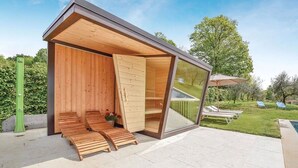 A modern outdoor lounge area with wooden benches and a glass enclosure. - Stunning private villa with WIFI, A/C, hot tub, private pool, sauna, TV and pets allowed (Montebelluna)