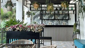 A modern interior with wicker furniture, hanging plants, and a blue sofa. - Alta Terra Hotel Tagaytay (Tagaytay)