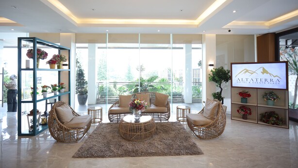 A spacious lobby with wicker furniture, a large chandelier, and a television displaying the hotel name. - Alta Terra Hotel Tagaytay (Tagaytay)