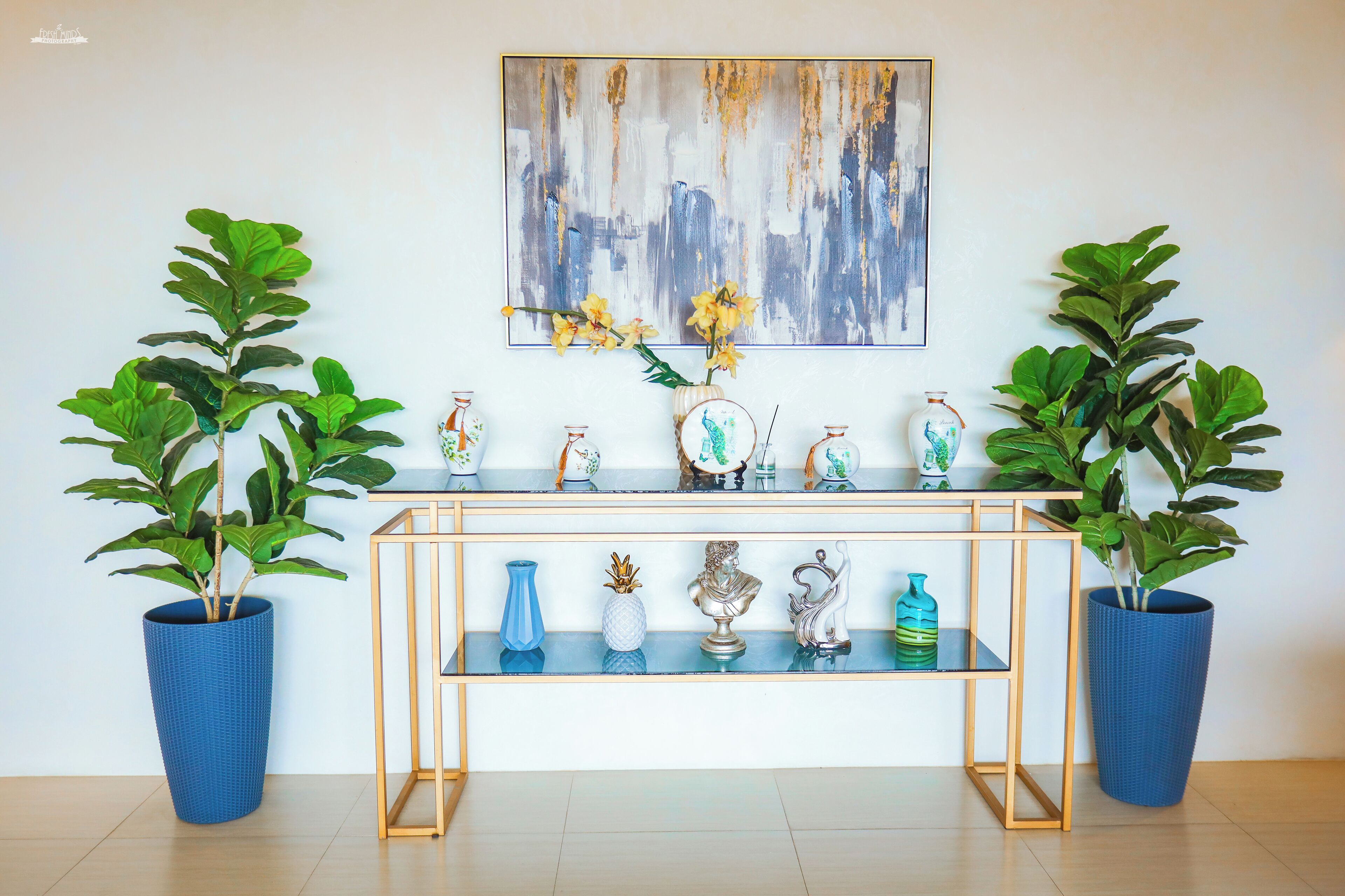Una habitación con una consola de madera que exhibe objetos decorativos y dos plantas en macetas.