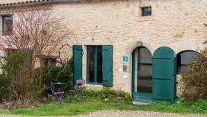 Un bâtiment en pierre avec une porte, des fenêtres et une petite enseigne.