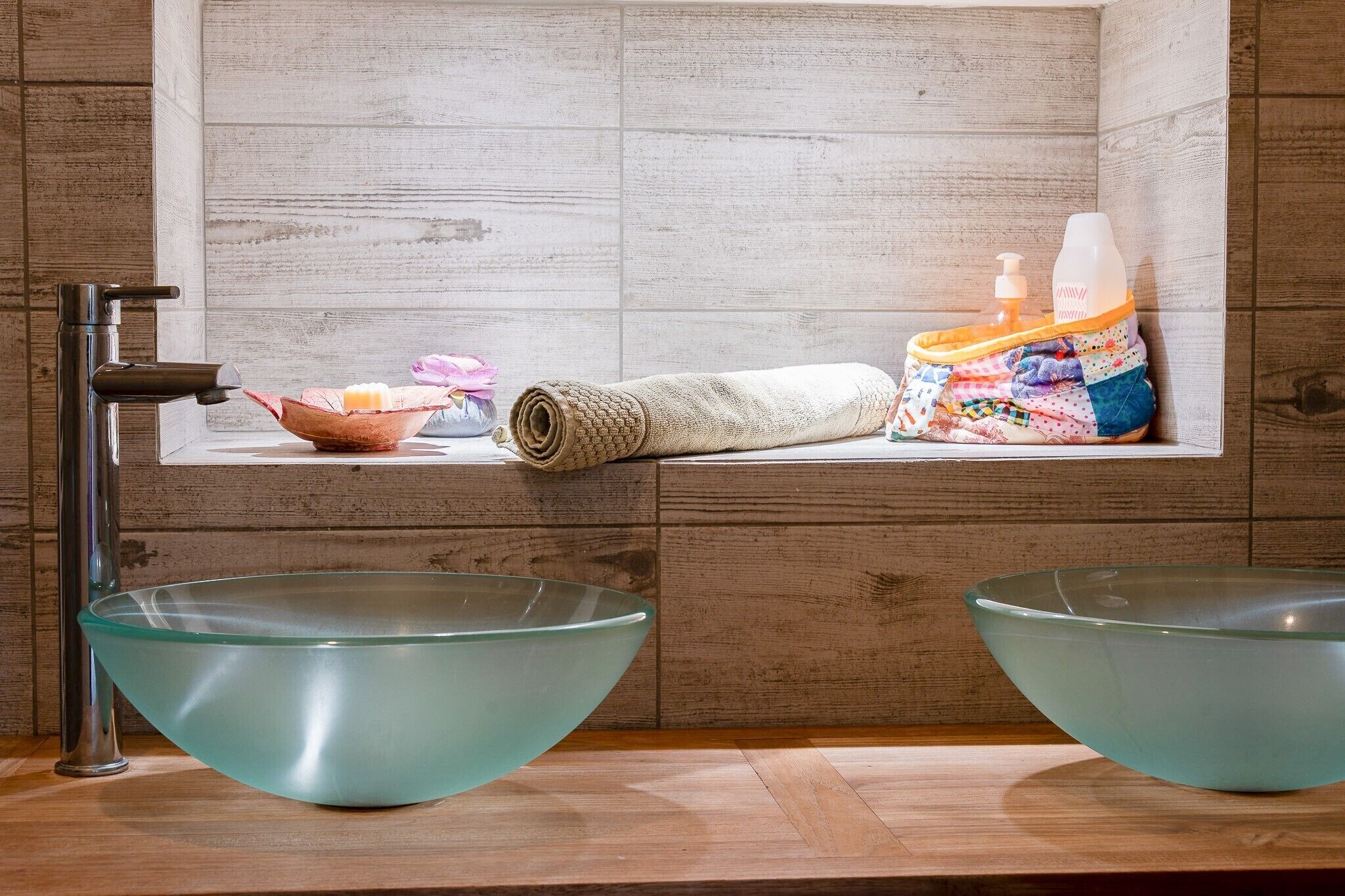 Ein Badezimmer mit zwei großen Glasvasen, einem Handtuch, einer Seifenspender und einer kleinen Schale mit einer rosa Blume.