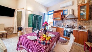 A dining area with a table set for two, a kitchen with a stove and oven, and a stone wall. - Tenuta Apollonio Pool & Relax (Carpignano Salentino)