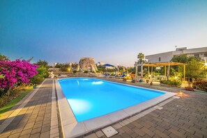 Ein Pool mit Liegestühlen und einer Steinstruktur im Hintergrund.