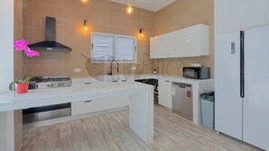 A modern kitchen with a central island, white cabinetry, a microwave, a dishwasher, and a gas stove.