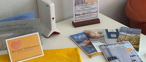 A table with a white device, a welcome card, brochures, and a yellow bag with the Immoog logo.