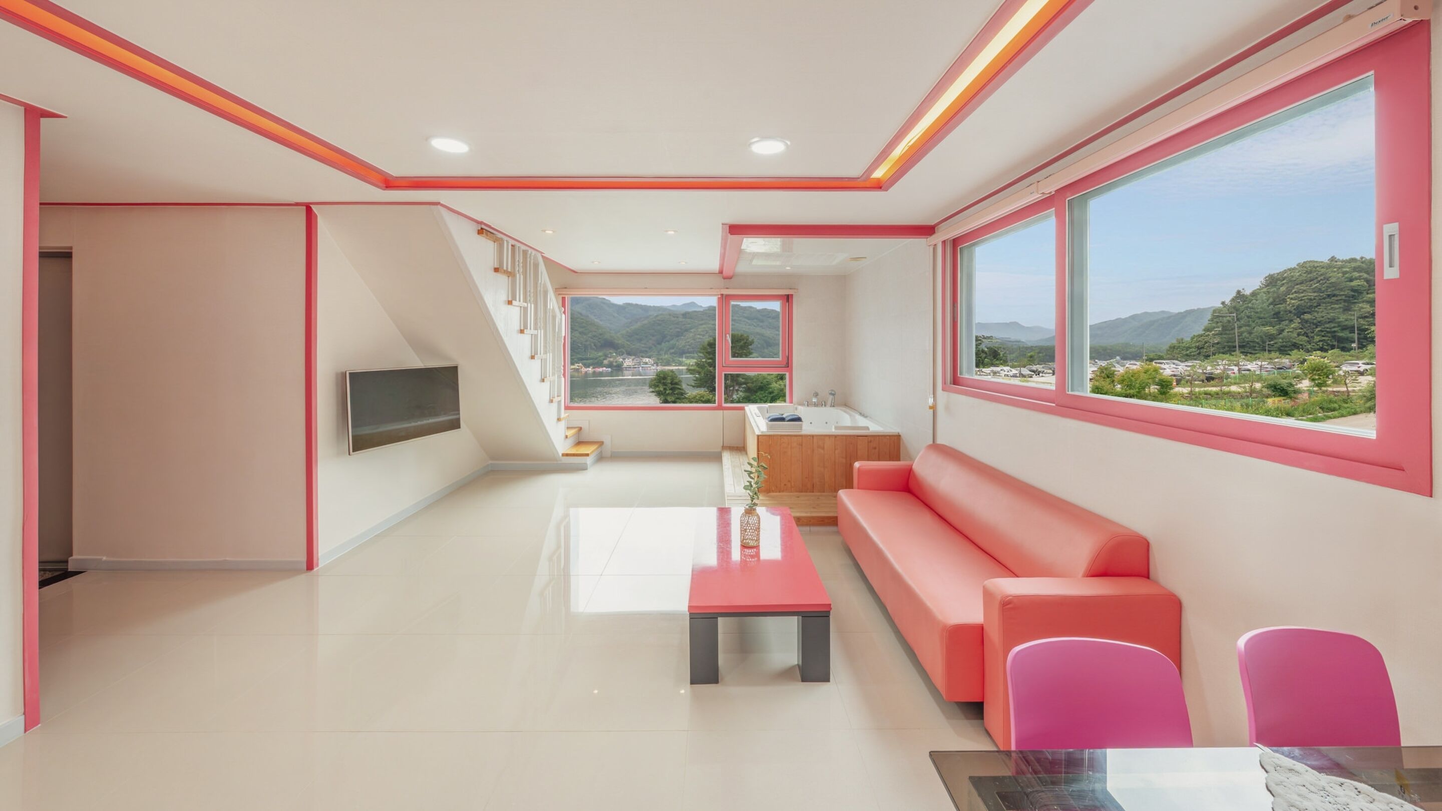 Un interior moderno con un ventanal grande, un sofá, una mesa y un televisor.