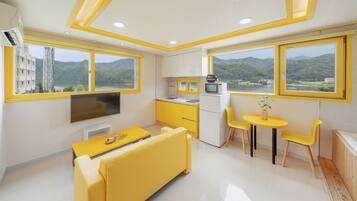 A modern kitchen with yellow cabinets, a dining area with yellow chairs, and large windows offering scenic mountain views.