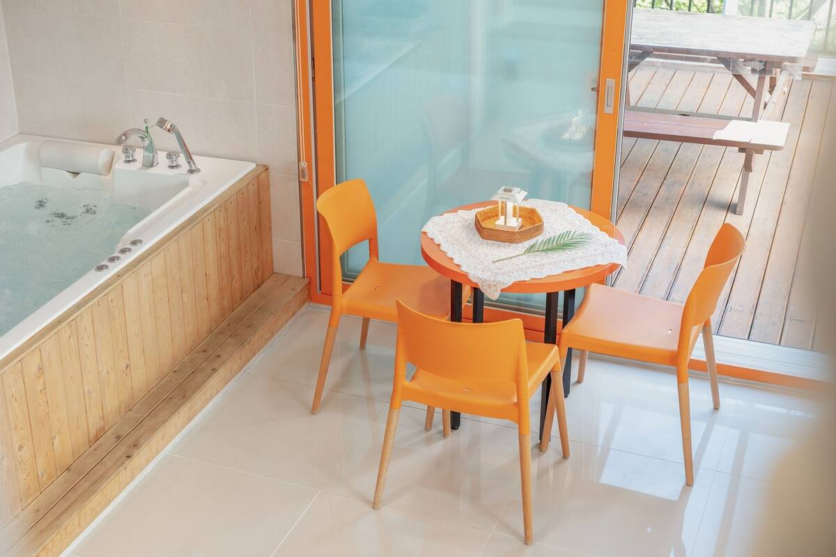 Ein Badezimmer mit einer Holzbadewanne, einer Duschkabine aus Glas und einem Tisch mit Stühlen.