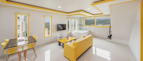 A modern living room with a yellow sofa, a glass dining table, and a TV.