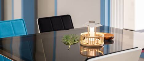 Una mesa de conferencias con una lámpara moderna, una planta en maceta y una maqueta de una casa encima.