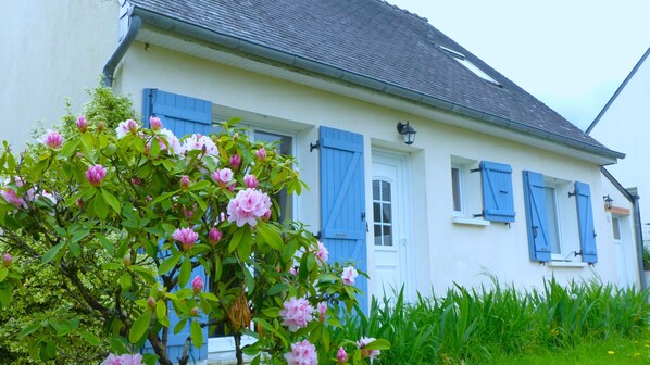 A white building with blue shutters, a door, and windows.