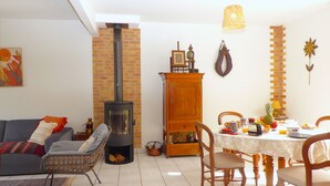 Una sala de estar acogedora con chimenea, una mesa de comedor lista para el desayuno y un espacio de estar cómodo.