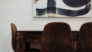 Een eetruimte met een houten tafel en drie gestoffeerde stoelen.