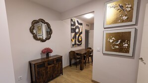 Een gang met een houten kast, een spiegel en drie ingelijste kunstwerken aan de muur.