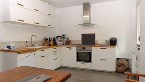 A compact kitchen with white cabinets, a stainless steel range hood, a built-in oven, and a wooden countertop. - Holiday home 2 km from the beach (Arradon)