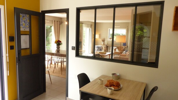 A dining area with a table set for two, a bowl of croissants, and a cup of coffee.