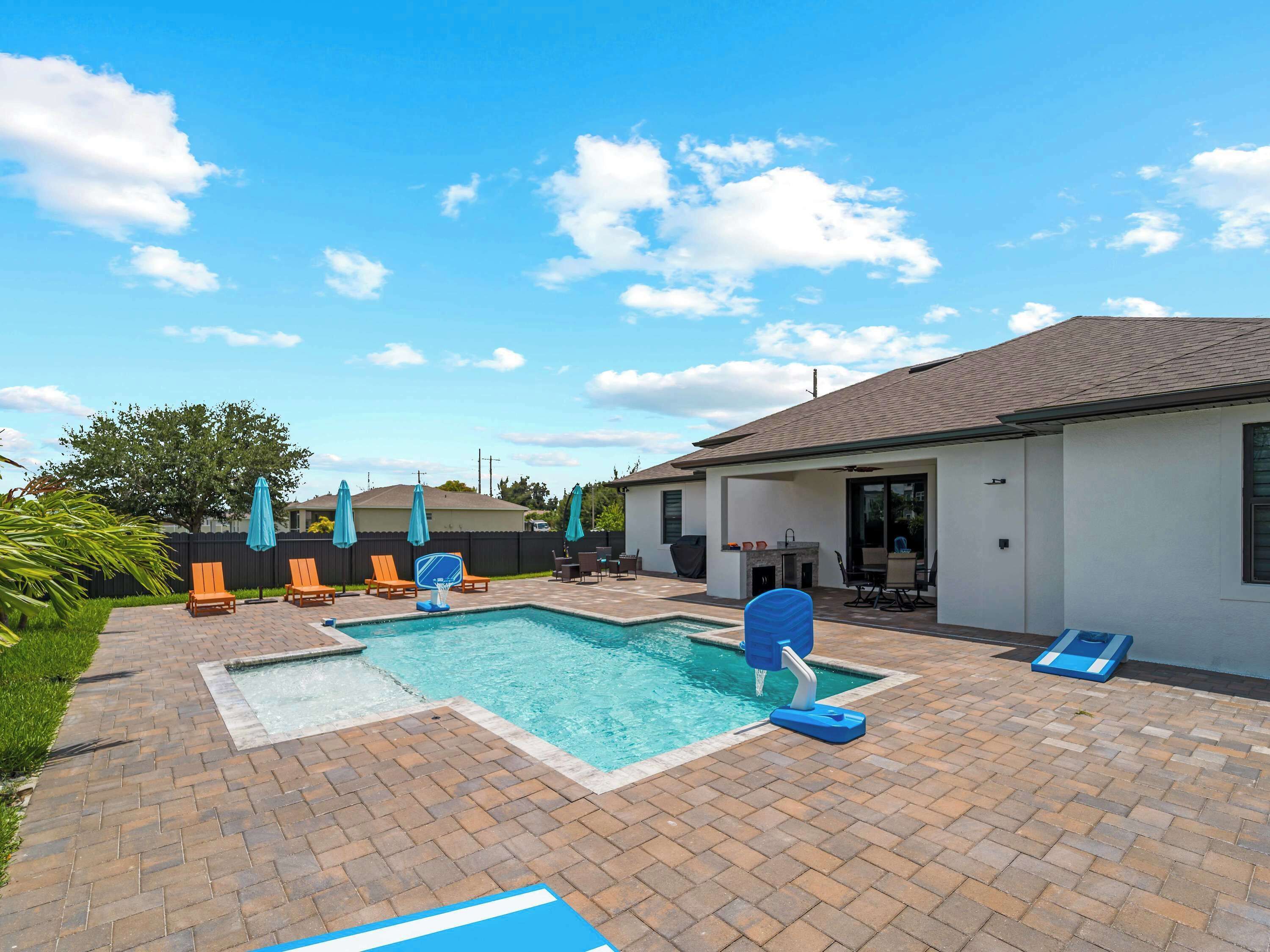 Ein Garten mit Pool, Liegestühlen und einer Terrasse.