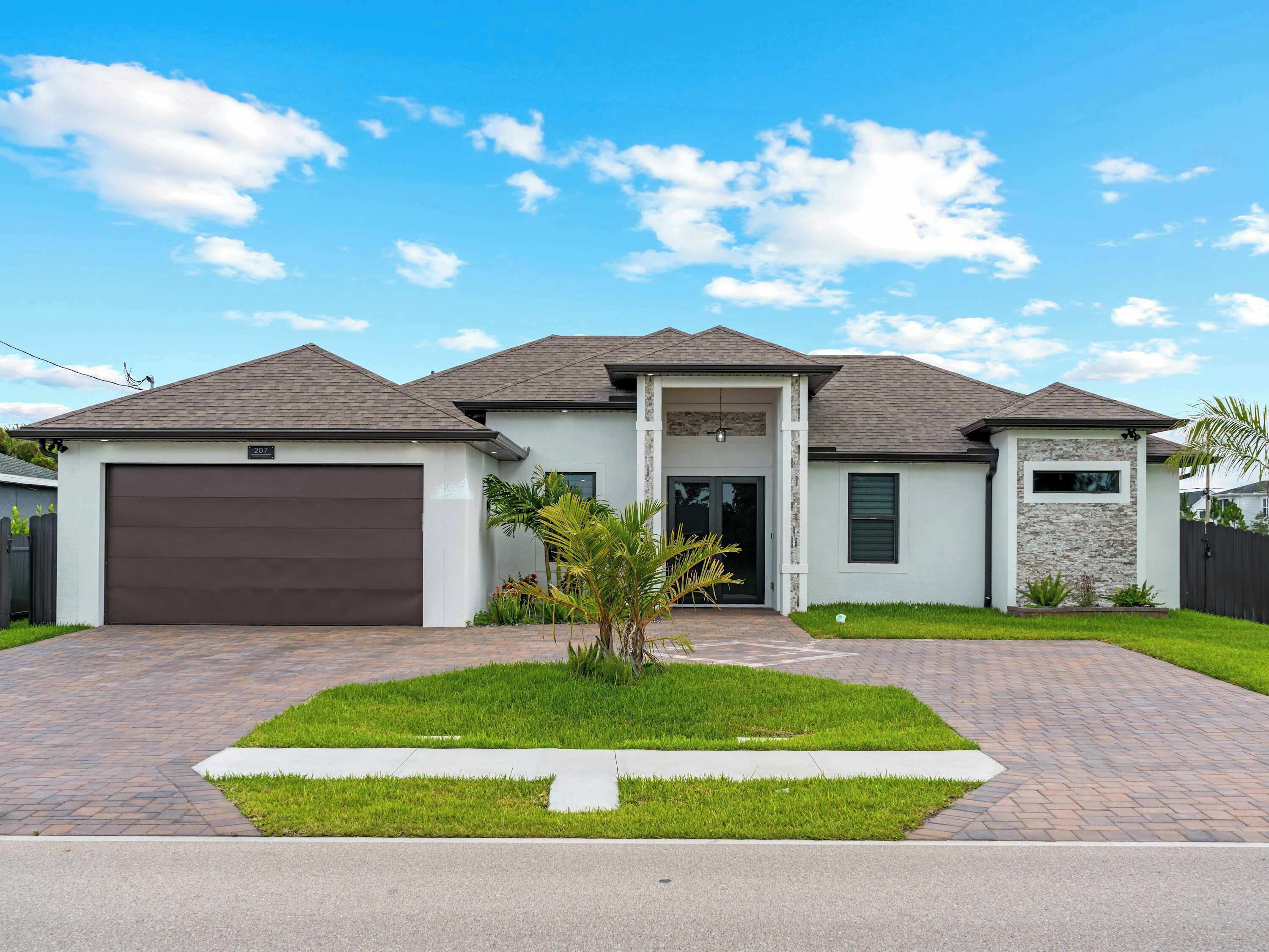 A modern two-story house with a garage, a front porch, and a well-maintained lawn.