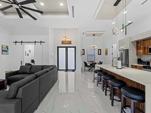 A modern kitchen with a central island, bar stools, and a dining area with chairs.
