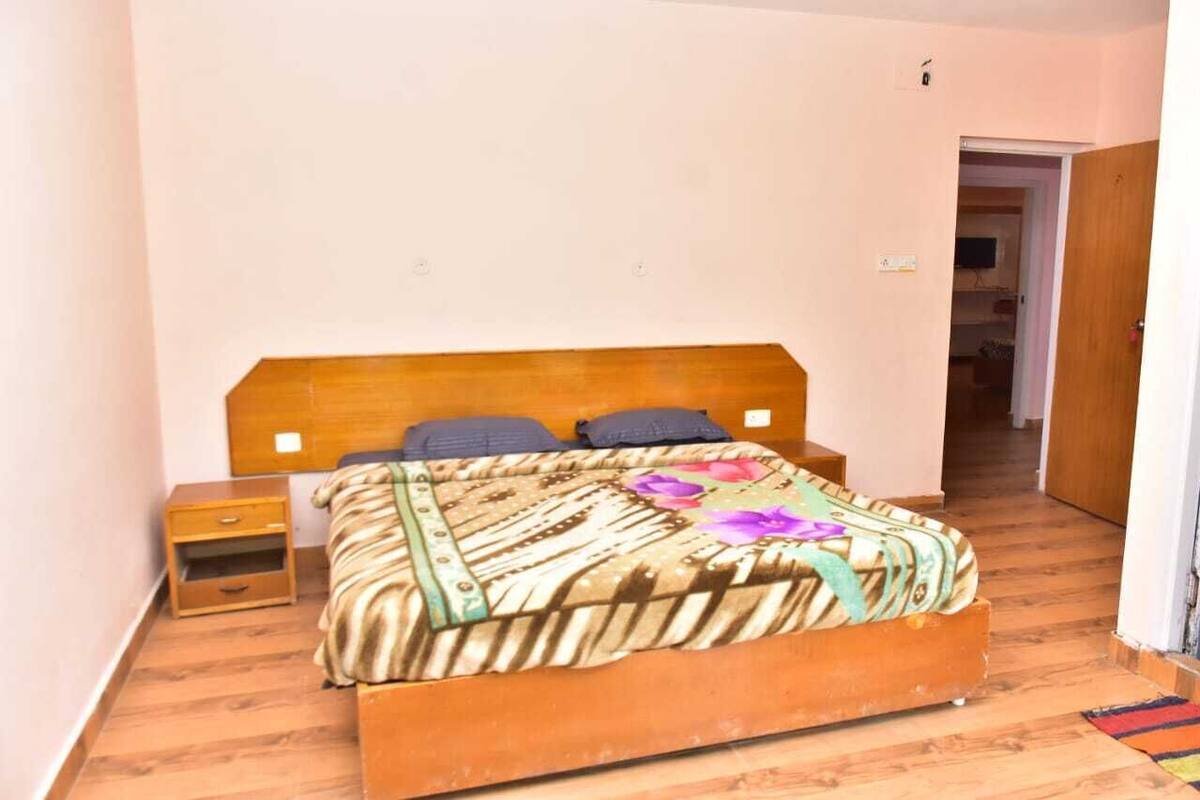 A bedroom with a wooden bed, a nightstand, and a door leading to another room.