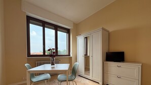 Una habitación con una mesa de comedor, dos sillas, un armario y un televisor.