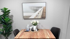 A dining area with a wooden table, black chairs, a potted plant, a remote control, a tissue box, a salt and pepper set, and a vase with white flowers. - Duluth Delight #1 Sum (Sioux Falls)