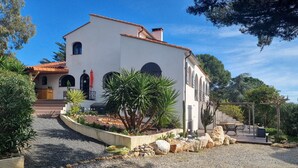 A white building with a tiled roof, a gravel driveway, and a garden with cacti and rocks. - 5 mns from the sea and 10 mns from Perpignan by car, 2-room apartment in the heart of nature. (Canet-en-Roussillon)