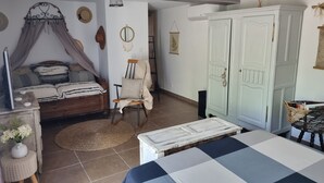 A bedroom with a bed, a chair, a wardrobe, and a small table. - 5 mns from the sea and 10 mns from Perpignan by car, 2-room apartment in the heart of nature. (Canet-en-Roussillon)