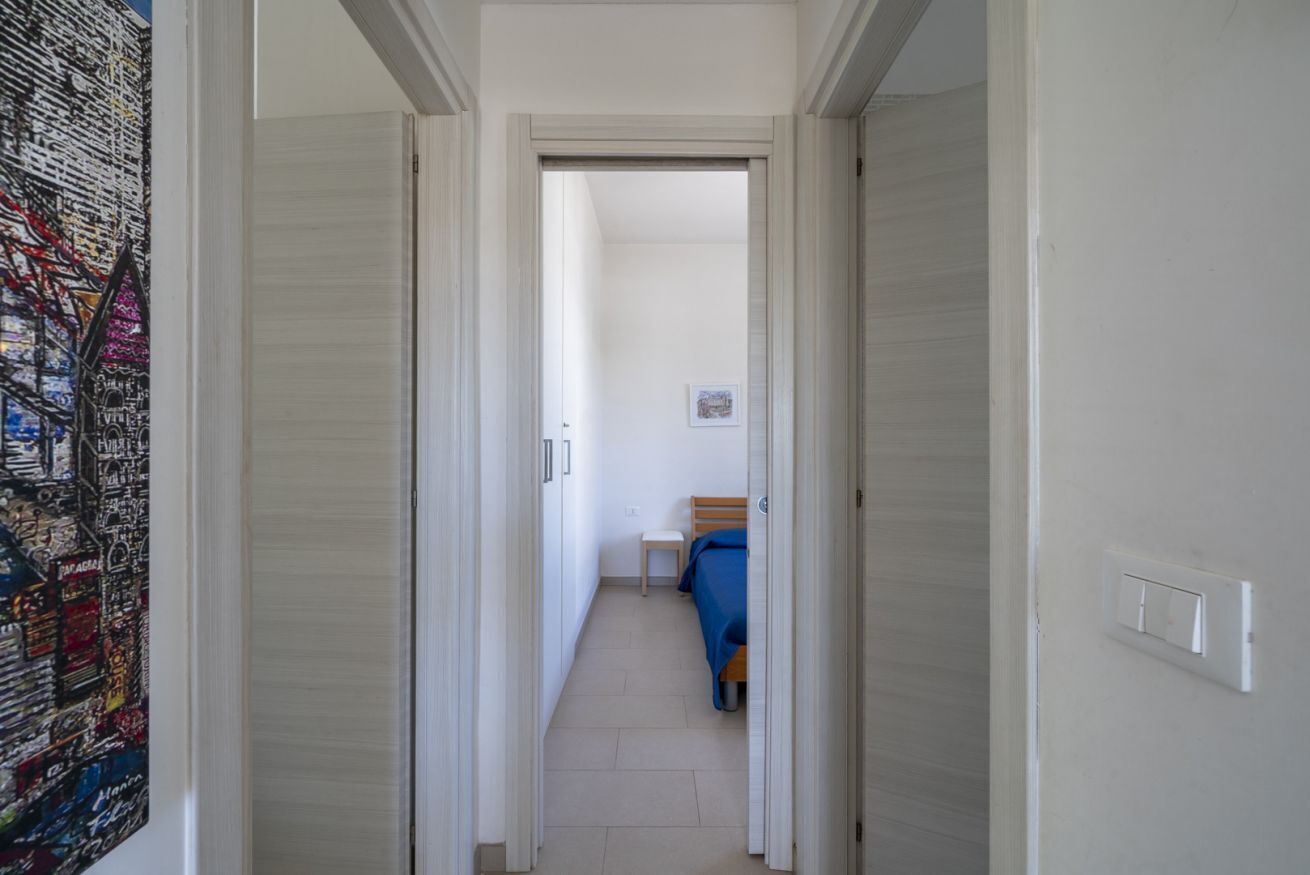 En smal hall som leder till ett sovrum med en säng och ett litet bord.