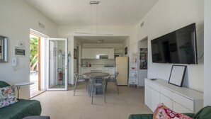 Un saló modern amb un sofà, una televisió i una zona de menjador amb taula i cadires.