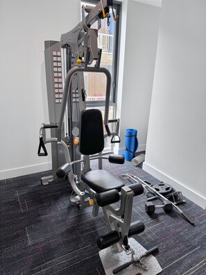 A gym with a variety of exercise equipment, including a bench press, dumbbells, and a weight machine. - 2 Bedroom Broadbeach Stay – Walk to Beach (Broadbeach)