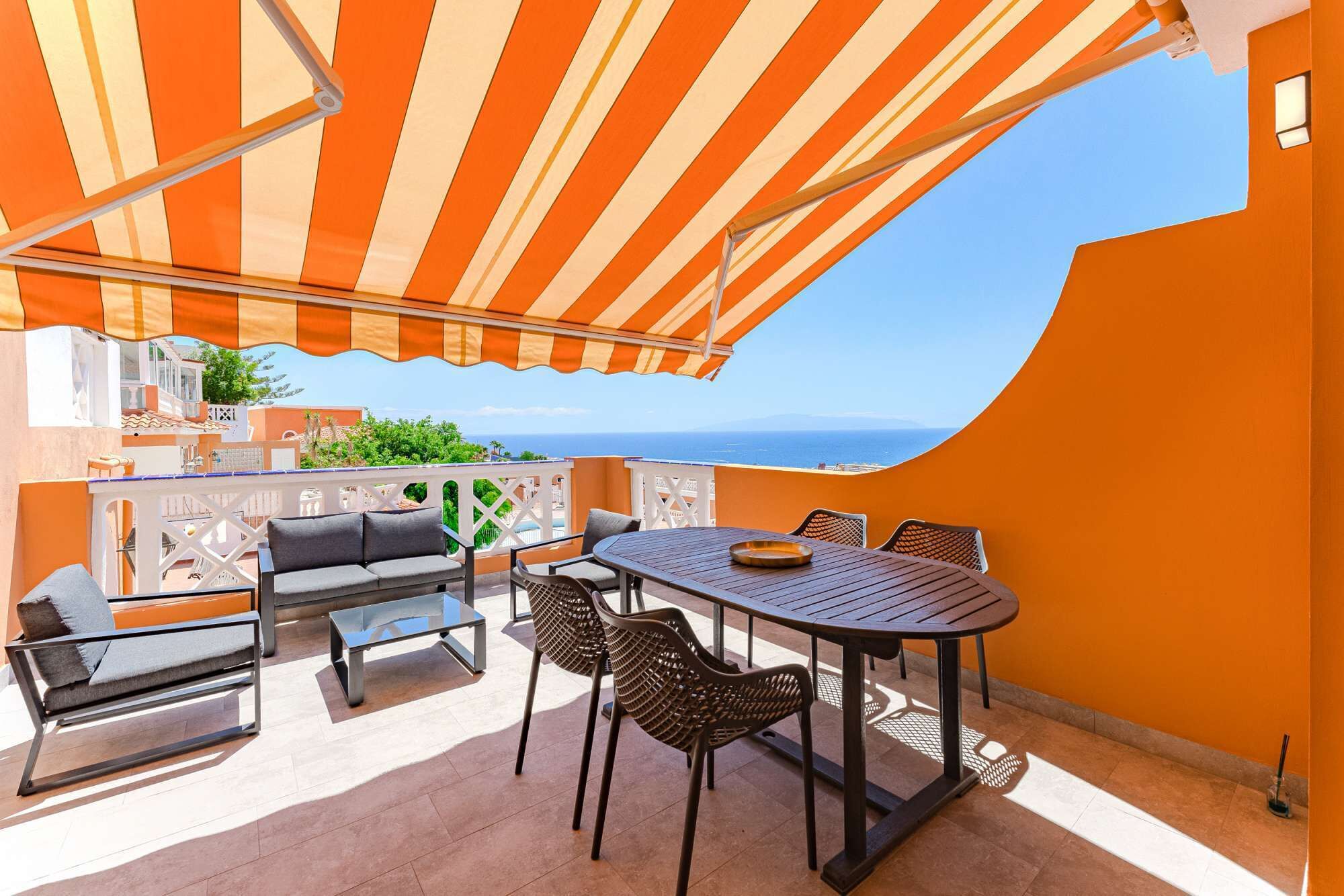 Un patio al aire libre con un toldo a rayas, una mesa redonda y dos sofás.