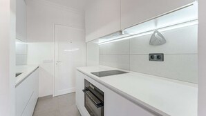 A modern kitchen with white cabinetry, a built-in oven, and a backsplash with a stone accent.