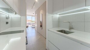 A modern kitchen with white cabinetry, a stainless steel sink, and under-cabinet lighting.