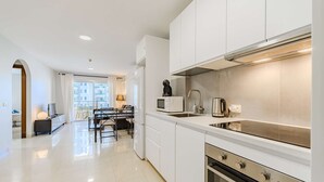 A modern kitchen with white cabinets, a stainless steel range hood, a built-in oven, and a large window providing natural light. - Sol Paraiso 2 bedrooms apartment (Adeje)